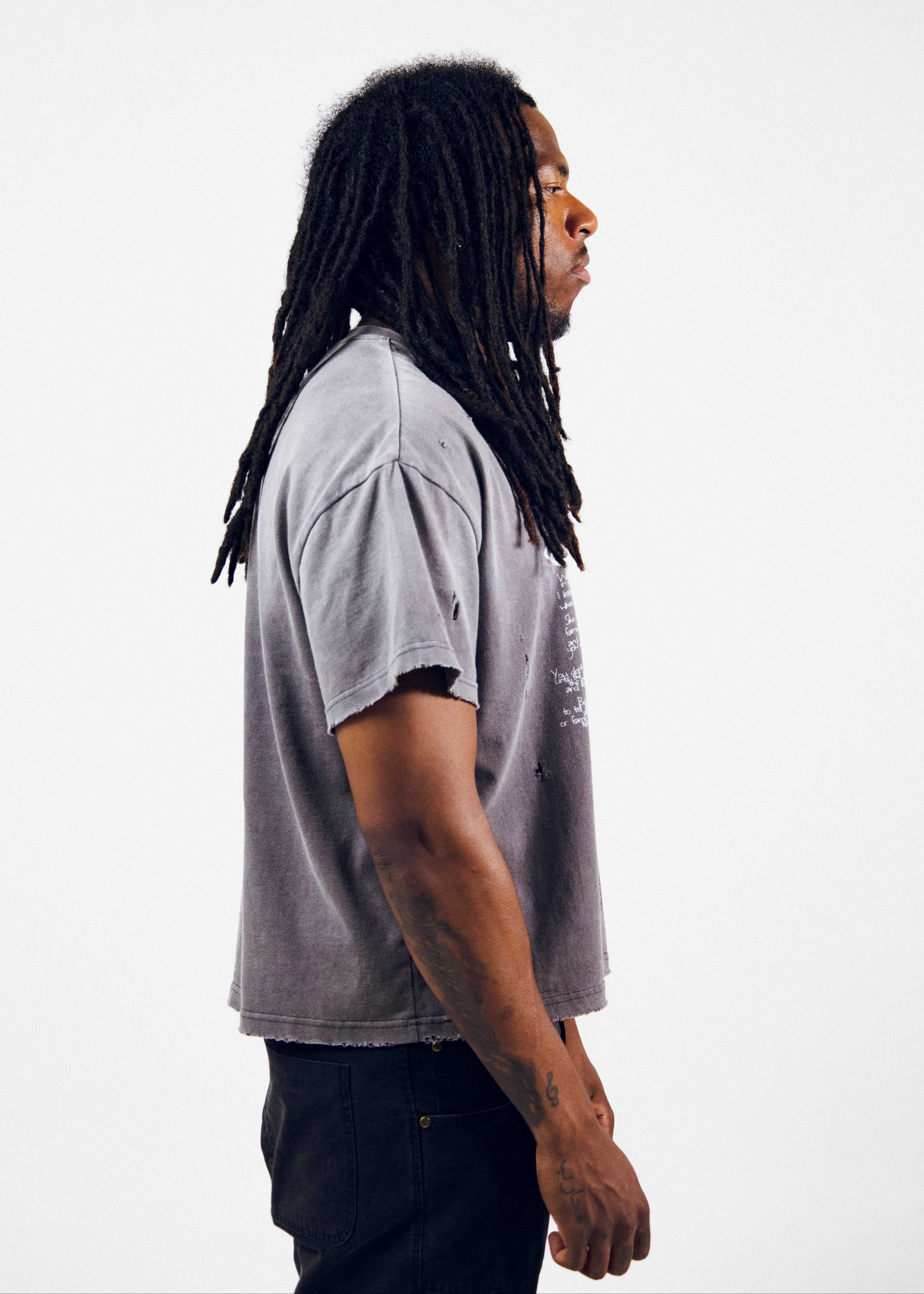 Fear Kills Art charcoal grey cotton t-shirt with loose fit, faded wash, distressed raw edges, and layered graphic print worn by model